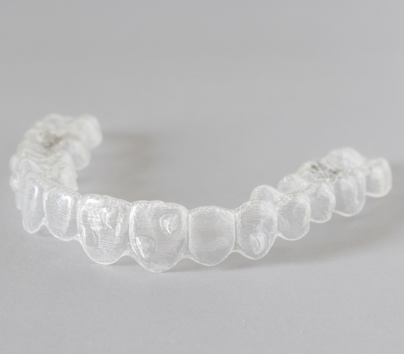 Close up view of invisalign braces or invisible retainers on grey background, new orthodontic equipment